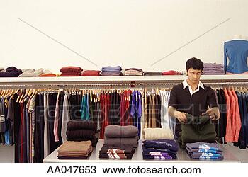 Stock Photo - young man folding 
sweater in clothing 
store. fotosearch 
- search stock 
photos, pictures, 
images, and photo 
clipart