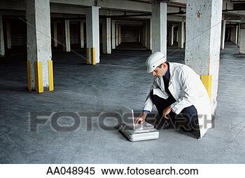 Stock Image - technician using 
laptop computer 
in empty warehouse. 
fotosearch - search 
stock photos, 
pictures, images, 
and photo clipart