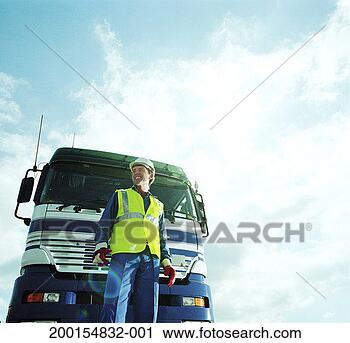 Stock Photography - man wearing hardhat 
standing in front 
of lorry, low 
angle view. fotosearch 
- search stock 
photos, pictures, 
images, and photo 
clipart