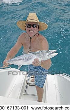 Stock Photography - mature man holding 
fish at stern 
of boat, smiling, 
elevated view. 
fotosearch - search 
stock photos, 
pictures, images, 
and photo clipart