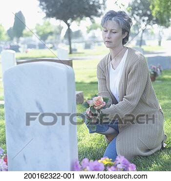 Stock Photography - mature woman kneeling 
beside tombstone, 
holding flowers. 
fotosearch - search 
stock photos, 
pictures, images, 
and photo clipart