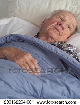 Stock Photography - senior man lying 
in bed, looking 
away, elevated 
view. fotosearch 
- search stock 
photos, pictures, 
images, and photo 
clipart