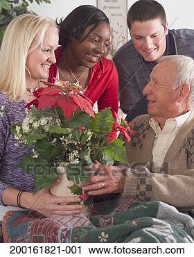 Stock Photography - three young adults 
giving poinsettia 
to senior man, 
smiling. fotosearch 
- search stock 
photos, pictures, 
images, and photo 
clipart