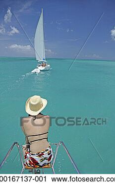 Stock Photography - woman sitting 
at bow of boat 
in tropical water, 
rear view. fotosearch 
- search stock 
photos, pictures, 
images, and photo 
clipart