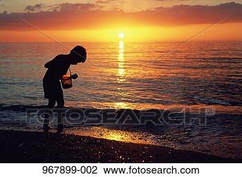 Stock Photo - boy holding bucket 
on beach silhouetted 
at sunset. fotosearch 
- search stock 
photos, pictures, 
images, and photo 
clipart