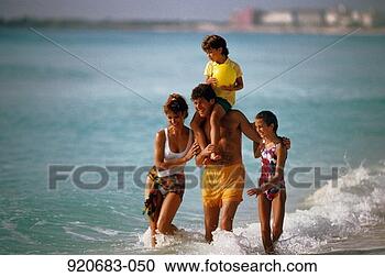 Stock Photography - family of four 
walking along 
beach, boy(6-8)on 
father's shoulders. 
fotosearch - search 
stock photos, 
pictures, images, 
and photo clipart
