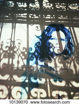 Stock Photography - woman's face projected 
on wall behind 
fence (digital 
composite). fotosearch 
- search stock 
photos, pictures, 
images, and photo 
clipart