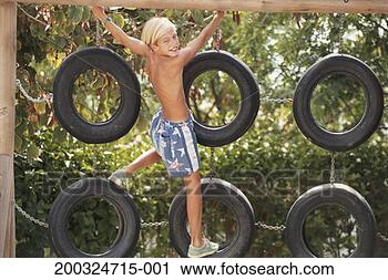 Stock Photography - boy (10-11) climbing 
on tyres, portrait. 
fotosearch - search 
stock photos, 
pictures, images, 
and photo clipart