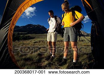 Stock Photography - couple putting 
on backpacks in 
mountain area, 
viewed through 
tent flap. fotosearch 
- search stock 
photos, pictures, 
images, and photo 
clipart
