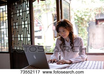 Foto - jovem,  mulher, 
 usando,  laptop, 
 dentro,  sorrindo. 
fotosearch - busca 
de fotos, imagens 
e clipart
