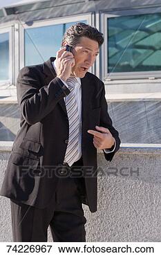 Picture - 'mature businessman 
using mobile phone, 
pulling facial 
expression'. fotosearch 
- search stock 
photos, pictures, 
images, and photo 
clipart