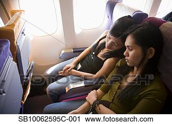 Arquivo de Fotografia - dois,   jovem, 
  mulheres,   
dormir,   contíguo, 
  assentos,   
avião. fotosearch 
- busca de fotos, 
imagens e clipart