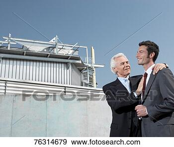 Stock Photograph - senior man putting 
arm around man 
in front of industrial 
building. fotosearch 
- search stock 
photos, pictures, 
images, and photo 
clipart