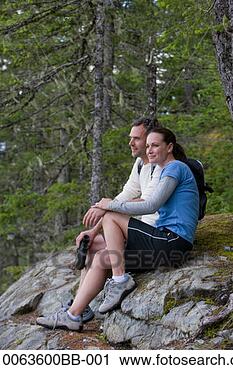 Stock Photography - couple sitting 
on boulder in 
forest, looking 
at view, side 
view. fotosearch 
- search stock 
photos, pictures, 
images, and photo 
clipart