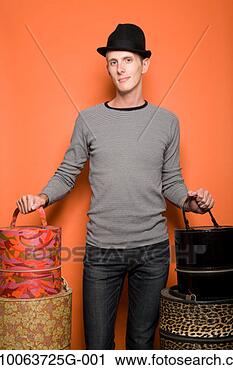 Stock Photography - young man wearing 
hat, standing 
and holding hat 
boxes, portrait. 
fotosearch - search 
stock photos, 
pictures, images, 
and photo clipart