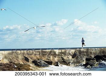 Stock Photography - young man running 
on sea wall, side 
view. fotosearch 
- search stock 
photos, pictures, 
images, and photo 
clipart