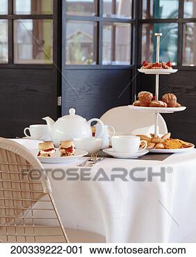 Stock Photography - table set for 
tea in conservatory, 
with scones and 
cakes on cake 
stand. fotosearch 
- search stock 
photos, pictures, 
images, and photo 
clipart