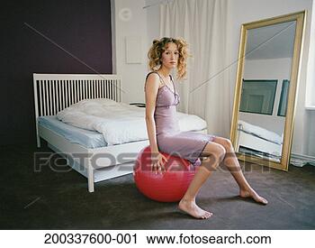 Stock Photography - young woman sitting 
on exercise ball 
in bedroom, portrait. 
fotosearch - search 
stock photos, 
pictures, images, 
and photo clipart