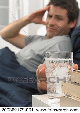 Stock Photography - man in bed, holding 
glass of water 
containing soluble 
tablet. fotosearch 
- search stock 
photos, pictures, 
images, and photo 
clipart