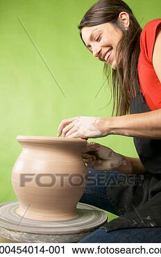Stock Photography - woman making vase 
on pottery wheel, 
smiling, low angle, 
side view. fotosearch 
- search stock 
photos, pictures, 
images, and photo 
clipart