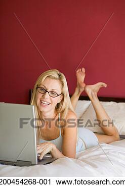Stock Photography - woman using laptop 
on bed, smiling. 
fotosearch - search 
stock photos, 
pictures, images, 
and photo clipart