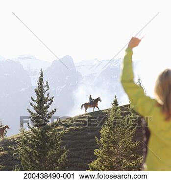 Stock Photography - woman waving at 
people horseback 
riding in mountains 
at sunset. fotosearch 
- search stock 
photos, pictures, 
images, and photo 
clipart