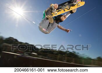 Stock Photography - young man performing 
trick on skateboard, 
low angle view. 
fotosearch - search 
stock photos, 
pictures, images, 
and photo clipart