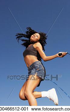 Stock Photography - young woman using 
skipping rope, 
low angle view, 
side view. fotosearch 
- search stock 
photos, pictures, 
images, and photo 
clipart
