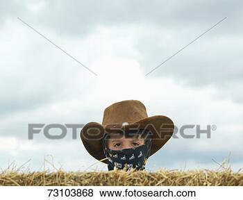 Stock Photo - cowboy (10-11) 
hiding behind 
hay bail, close-up, 
portrait. fotosearch 
- search stock 
photos, pictures, 
images, and photo 
clipart