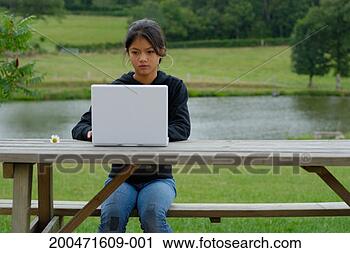 Stock Photography - girl (11-13) using 
laptop on garden 
furniture, outdoors. 
fotosearch - search 
stock photos, 
pictures, images, 
and photo clipart