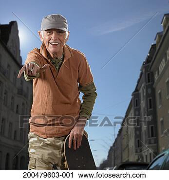 Stock Photography - senior man holding 
skateboard, making 
hand gesture, 
smiling, portrait. 
fotosearch - search 
stock photos, 
pictures, images, 
and photo clipart
