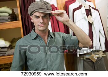 Stock Photograph - young man in clothes 
shop, trying on 
hat, portrait. 
fotosearch - search 
stock photos, 
pictures, images, 
and photo clipart