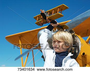 Banco de Imagem - menino,  ficar, 
 frente,  avião, 
 segurando,  brinquedo, 
 avião. fotosearch 
- busca de fotos, 
imagens e clipart