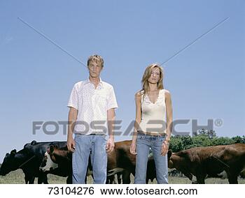 Stock Photo - young couple standing 
in field besides 
cow. fotosearch 
- search stock 
photos, pictures, 
images, and photo 
clipart