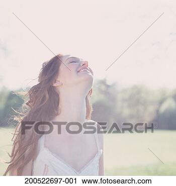 Stock Photography - young woman in 
field, smiling, 
looking up, close-up, 
(high key). fotosearch 
- search stock 
photos, pictures, 
images, and photo 
clipart