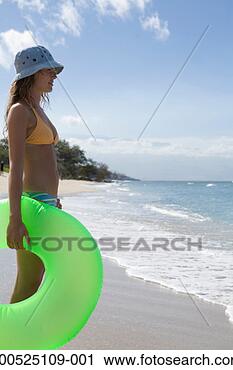 Stock Photography - young woman holding 
inflatable ring 
on beach, side 
view. fotosearch 
- search stock 
photos, pictures, 
images, and photo 
clipart