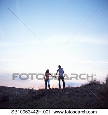 Stock Photography - young couple on 
sand dune, holding 
hands. fotosearch 
- search stock 
photos, pictures, 
images, and photo 
clipart