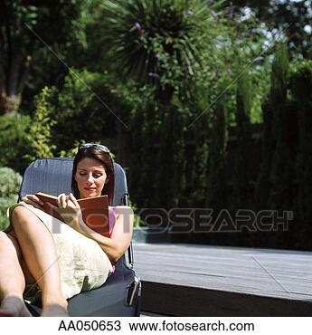 Stock Photo - young woman sitting 
on deck chair 
reading. fotosearch 
- search stock 
photos, pictures, 
images, and photo 
clipart
