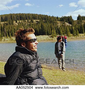 Stock Photo - two male hikers 
relaxing beside 
lake (selective 
focus). fotosearch 
- search stock 
photos, pictures, 
images, and photo 
clipart