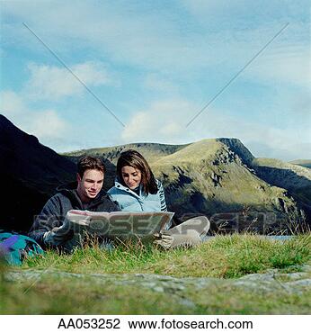 Stock Photo - young man and 
woman sitting 
on ground, looking 
at map. fotosearch 
- search stock 
photos, pictures, 
images, and photo 
clipart