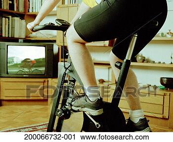 Stock Photography - man riding exercise 
bike, watching 
cyclist on television, 
low section. fotosearch 
- search stock 
photos, pictures, 
images, and photo 
clipart