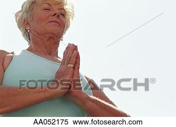 Stock Image - mature woman practicing 
yoga, hands pressed 
together, low 
angle view. fotosearch 
- search stock 
photos, pictures, 
images, and photo 
clipart