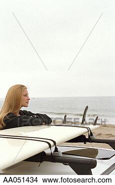 Stock Photo - young woman leaning 
on surfboard on 
top of car at 
beach, side view. 
fotosearch - search 
stock photos, 
pictures, images, 
and photo clipart