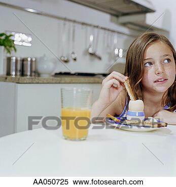 Stock Image - girl (8-10) dipping 
toast into boiled 
egg, looking away. 
fotosearch - search 
stock photos, 
pictures, images, 
and photo clipart