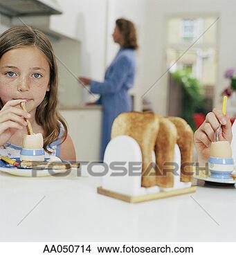 Stock Photo - girl (8-10) eating 
egg and bread, 
mom in background, 
portrait. fotosearch 
- search stock 
photos, pictures, 
images, and photo 
clipart