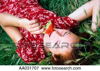 Picture - young woman eating 
watermerlon lying 
in grass. fotosearch 
- search stock 
photos, pictures, 
images, and photo 
clipart