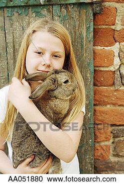 Stock Photography - girl (10-12) holding 
rabbit, leaning 
against fence. 
fotosearch - search 
stock photos, 
pictures, images, 
and photo clipart