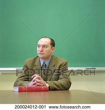 Arquivo de Fotografia - faculdade,  professor, 
 sentando,  escrivaninha, 
 quadro-negro, 
 fundo. fotosearch 
- busca de fotos, 
imagens e clipart