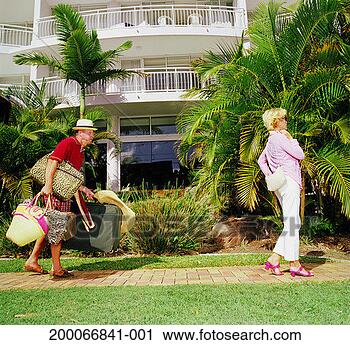 Stock Photography - mature couple 
at resort, man 
struggling with 
suitcases. fotosearch 
- search stock 
photos, pictures, 
images, and photo 
clipart