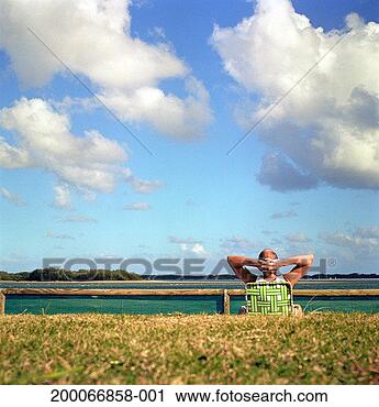Stock Photography - mature man relaxing 
in deck chair 
by sea, rear view. 
fotosearch - search 
stock photos, 
pictures, images, 
and photo clipart